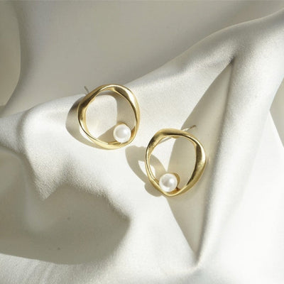 Emilia | Elegant gold earrings with a wave-shaped design and pearl details.