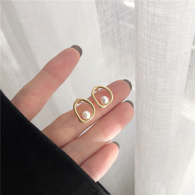 Emilia | Elegant gold earrings with a wave-shaped design and pearl details.